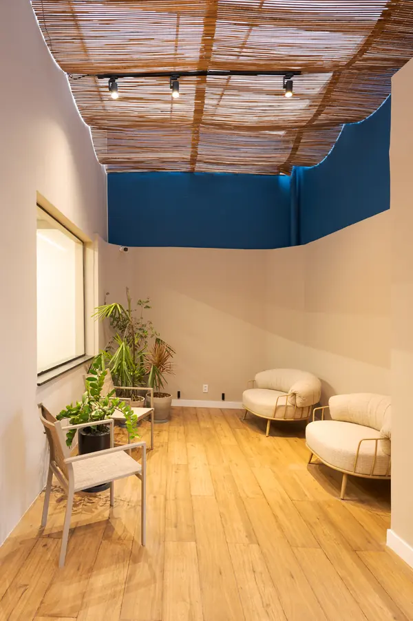 Lounge com poltronas, plantas e teto de bambu