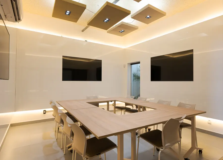 Sala climatizada com mesas em U e duas telas